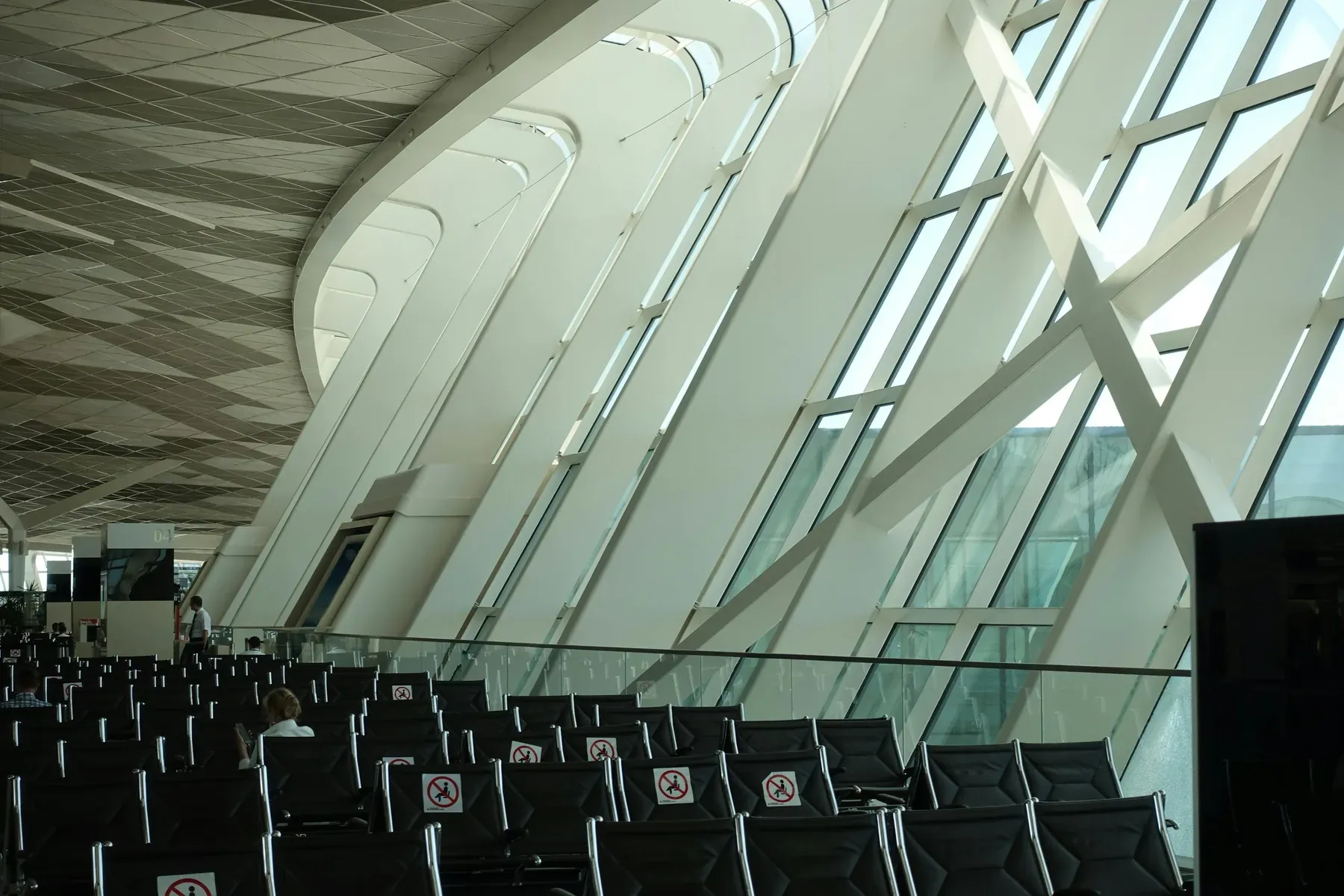 Airport departure hall with rows of empty seats and tall windows