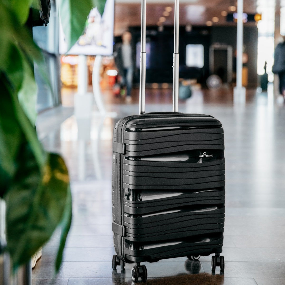 Svart kabinväska från North Pioneer på golvet i en flygplatshall